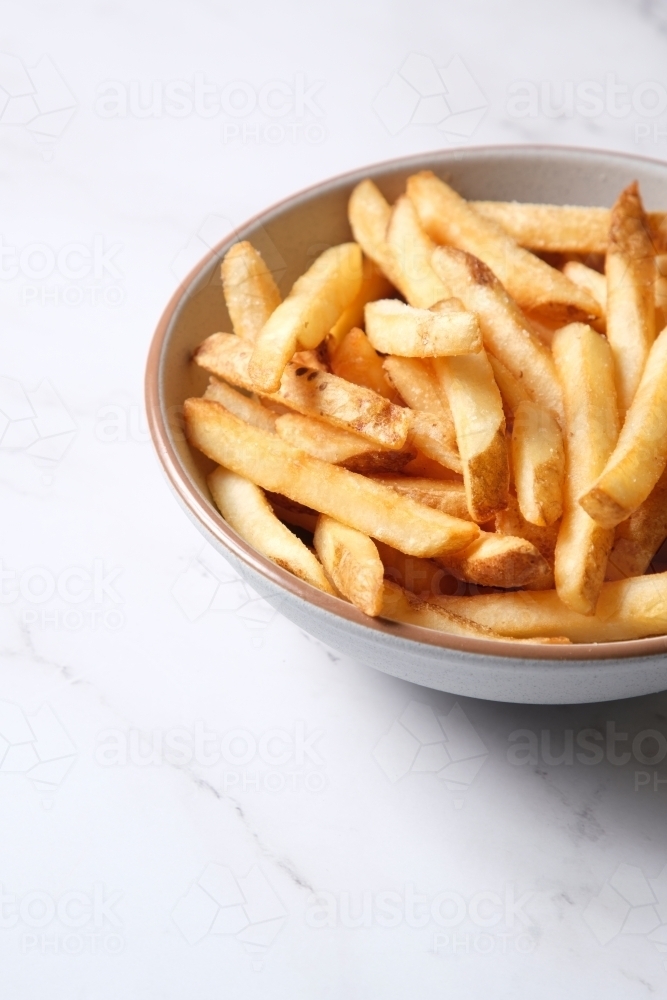 Bowl of hot chips on marble table - Australian Stock Image