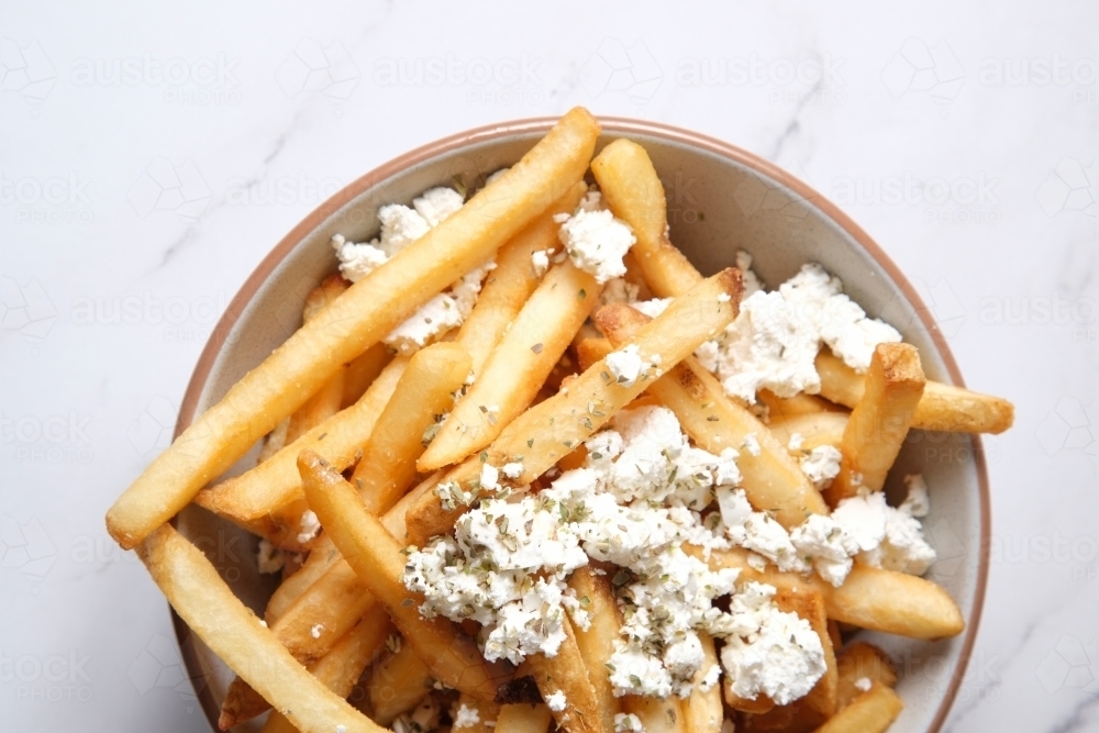 Bowl of hot chips with sprinkled feta cheese - Australian Stock Image