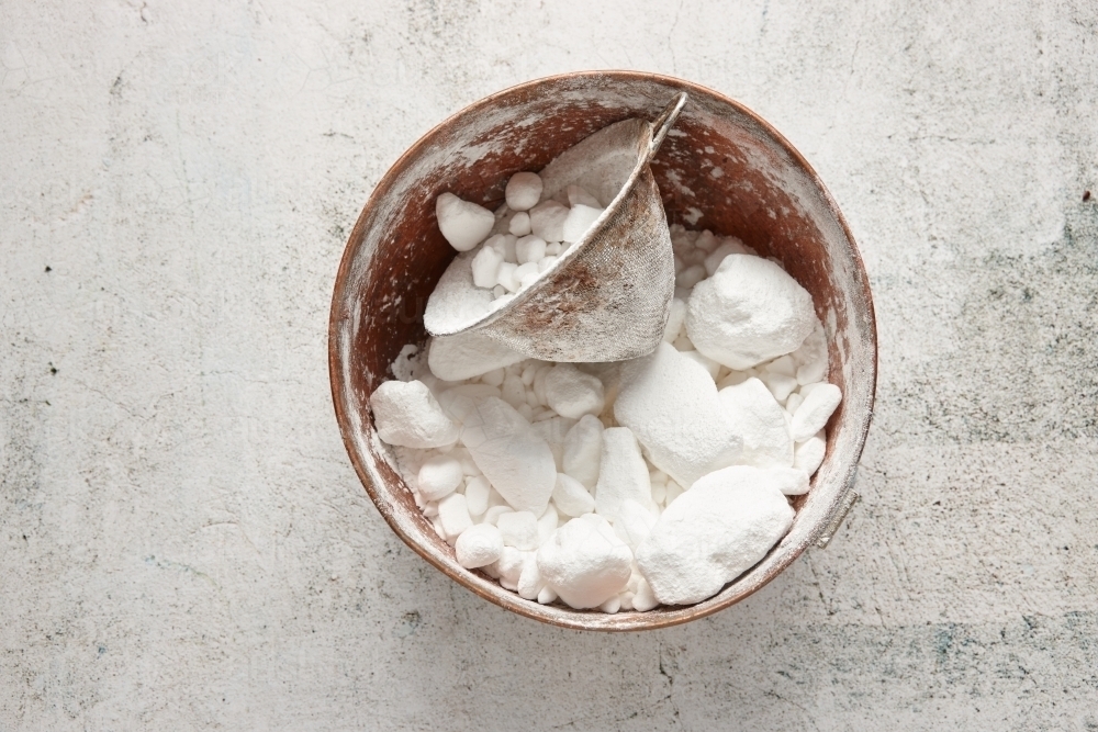 Bowl of lumpy icing sugar with sieve - Australian Stock Image