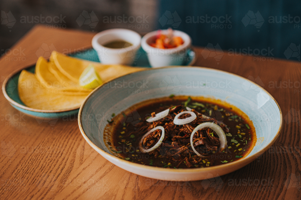 bowl of Mexican Stew birria Served With Tortillas and Garnishes - Australian Stock Image