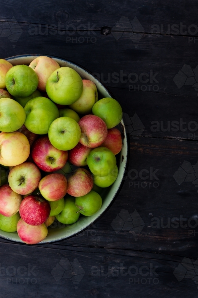 bowl of organic apples on a dark wooden background - Australian Stock Image