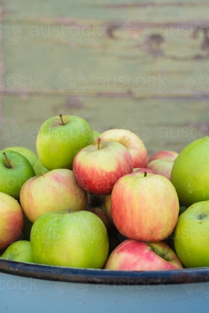 bowl of organic apples on a wooden background - Australian Stock Image