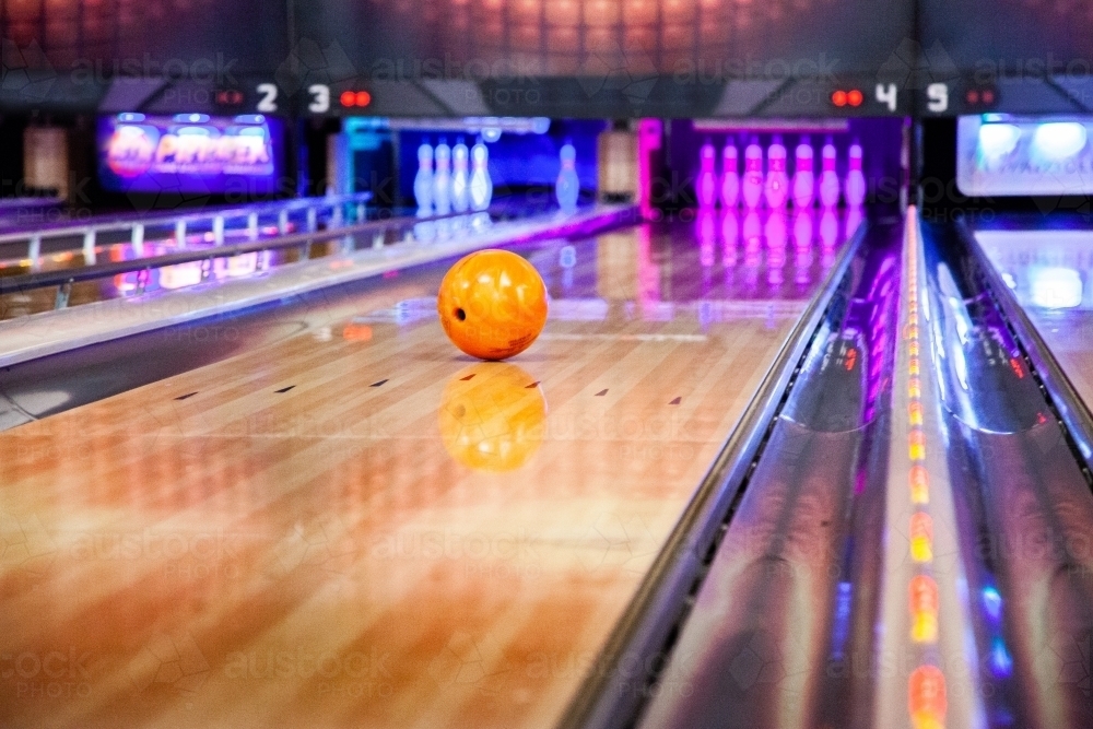 Bowling ball rolling towards pins at ten pin bowling alley - Australian Stock Image