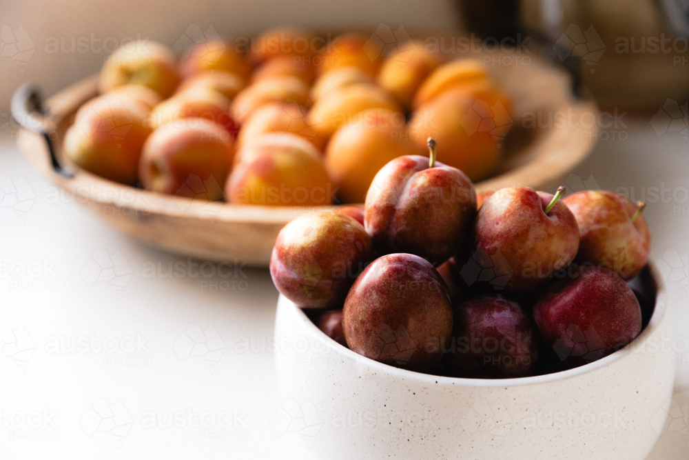 Bowls of freshly picked peaches and plums on kitchen bench - Australian Stock Image