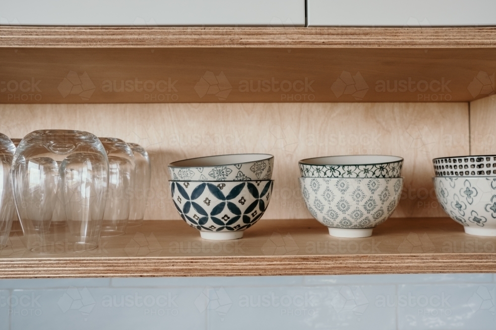 Bowls stacked on wooden shelf. - Australian Stock Image