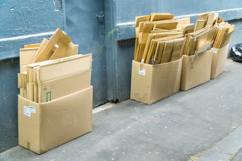 Boxes of cardboard stacked outside against a wall in an alley - Australian Stock Image