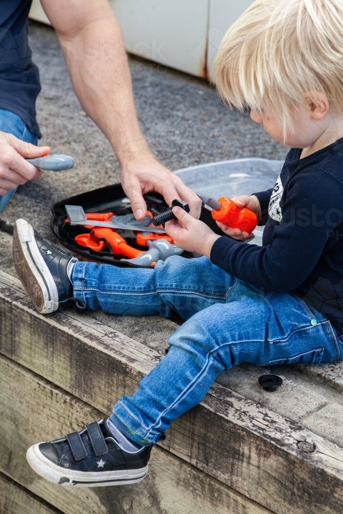 Boy and dad playing with plastic toy tools - Australian Stock Image