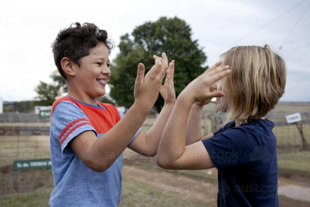 Boy and girl playing clapping game outside - Australian Stock Image