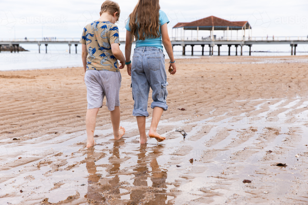 boy and girl walking on the beach near Redcliffe jetty - Australian Stock Image