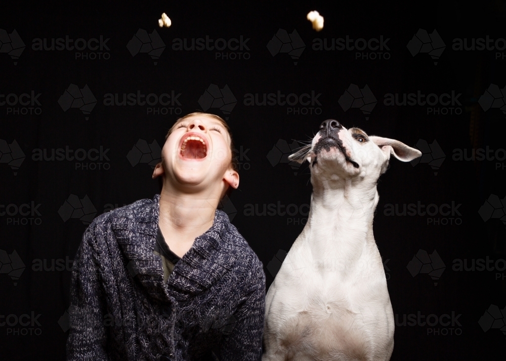 Boy and his dog in fun studio portrait on black - Australian Stock Image