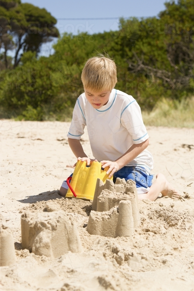 Boy building sand castle at the beach - Australian Stock Image