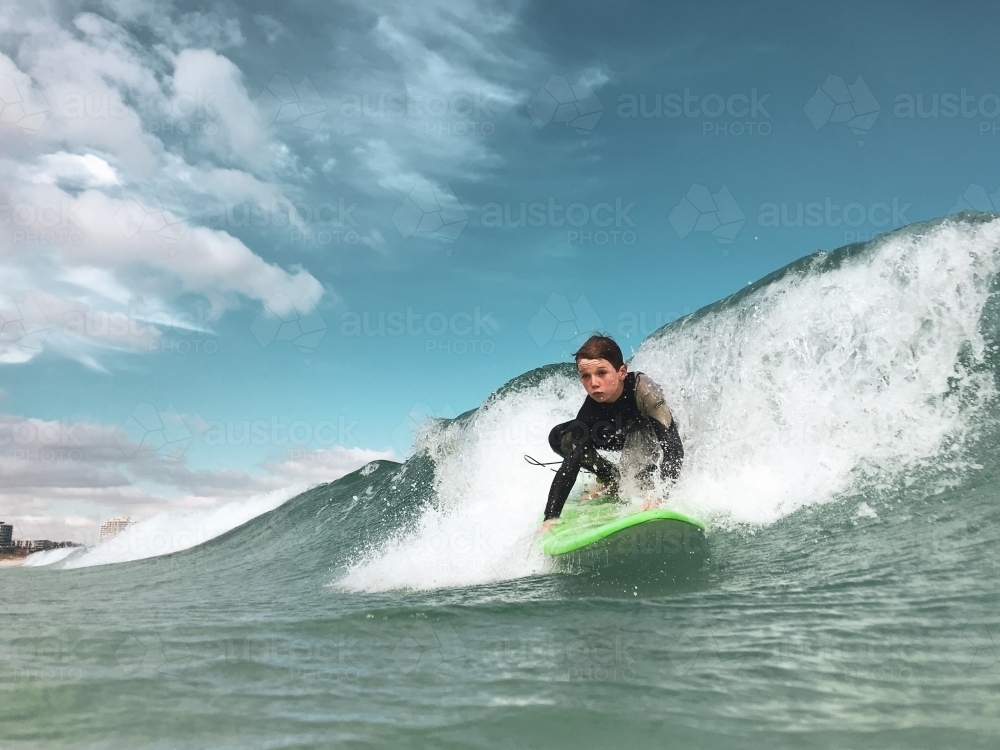 Boy catching wave on foam surfboard taken in water - Australian Stock Image
