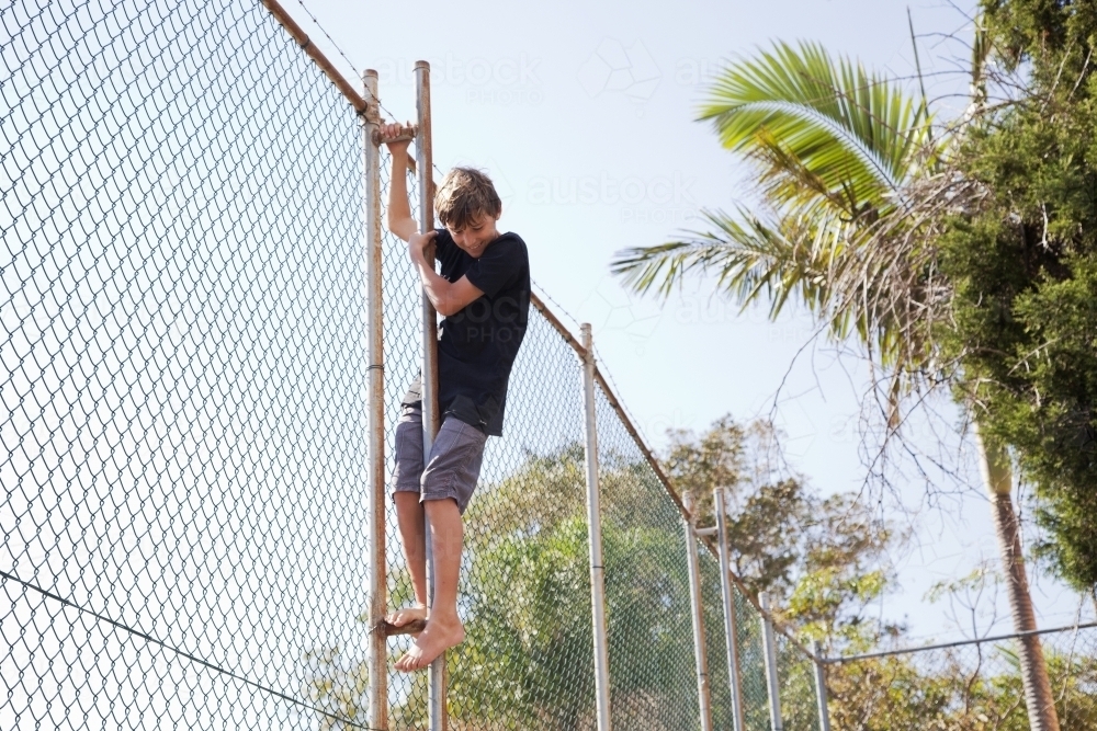 Boy climbing a fence - Australian Stock Image