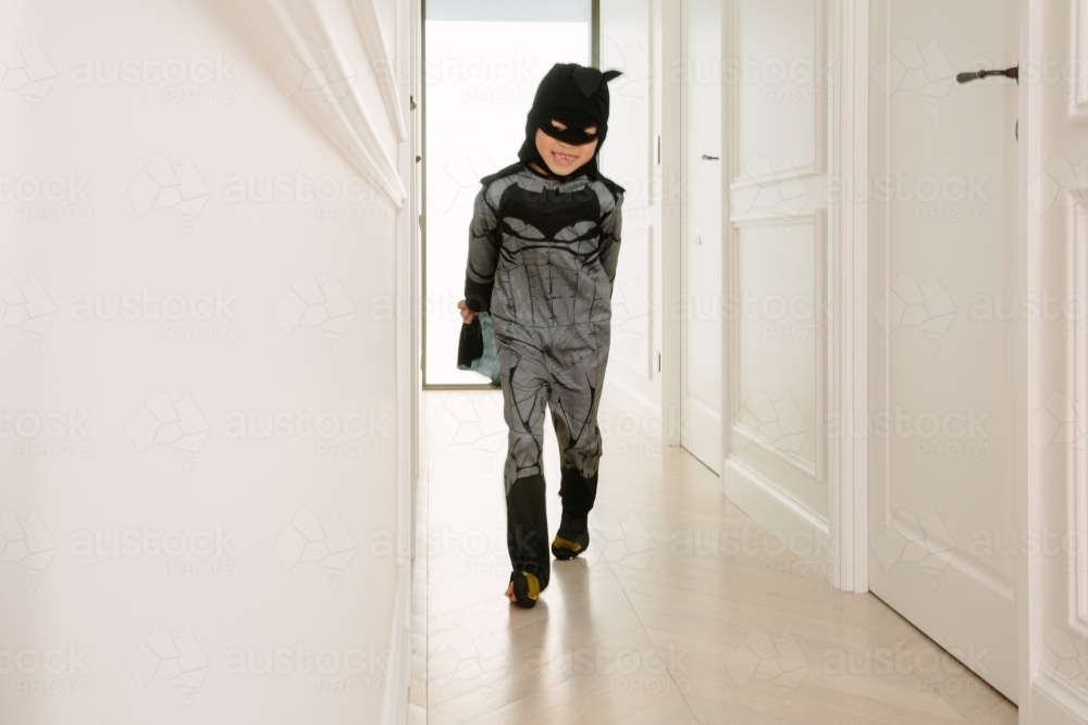 Boy dressed up as batman inside a white house - Australian Stock Image