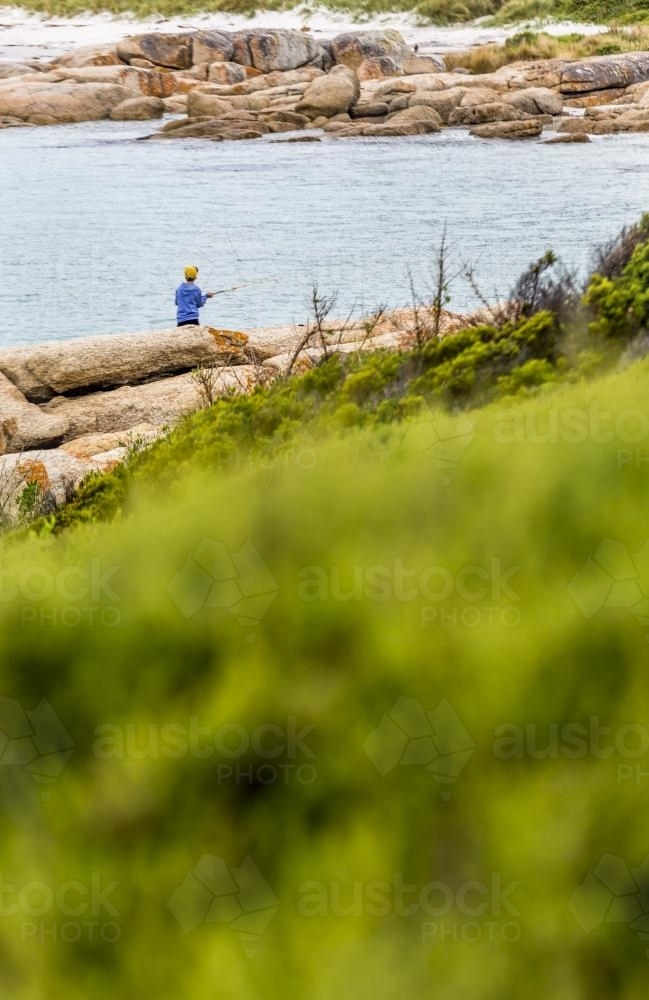Boy fishing off the rocks - Australian Stock Image