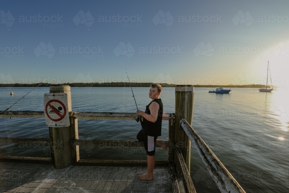 Boy fishing on jetty at Iluka, NSW Australia - Australian Stock Image