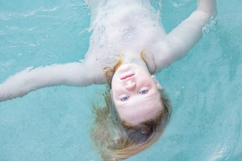 Image of Boy floating upside down vibrant blue swimming pool Austockphoto