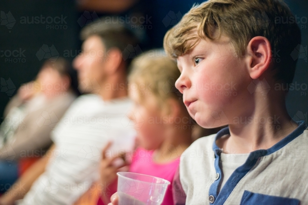Boy, girl and man in cinema watching movie - Australian Stock Image