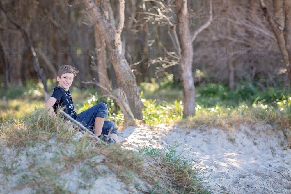 Boy having fun on the sand dunes on a remote beach in Queensand - Australian Stock Image