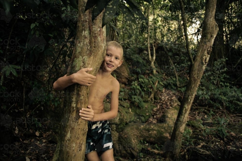 Boy hiding in the bush near a creek - Australian Stock Image