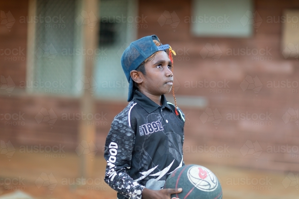 boy holding basketball and looking up at hoop - Australian Stock Image