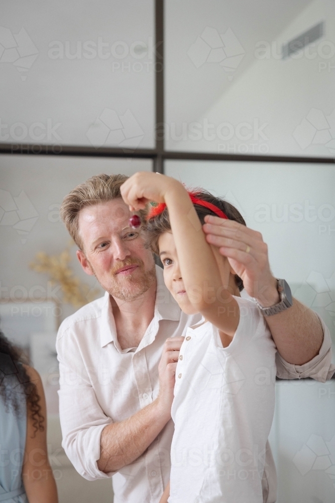 Boy holding cherry with dad - Australian Stock Image