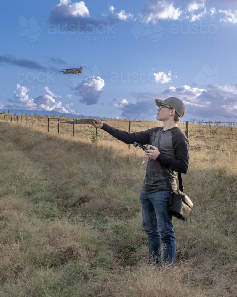Boy in a paddock with a drone under a blue sky - Australian Stock Image