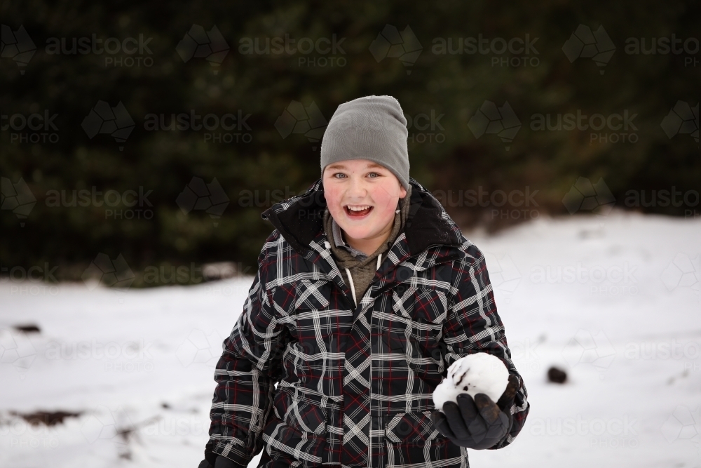 Boy in the snow with snow ball having snowball fight - Australian Stock Image