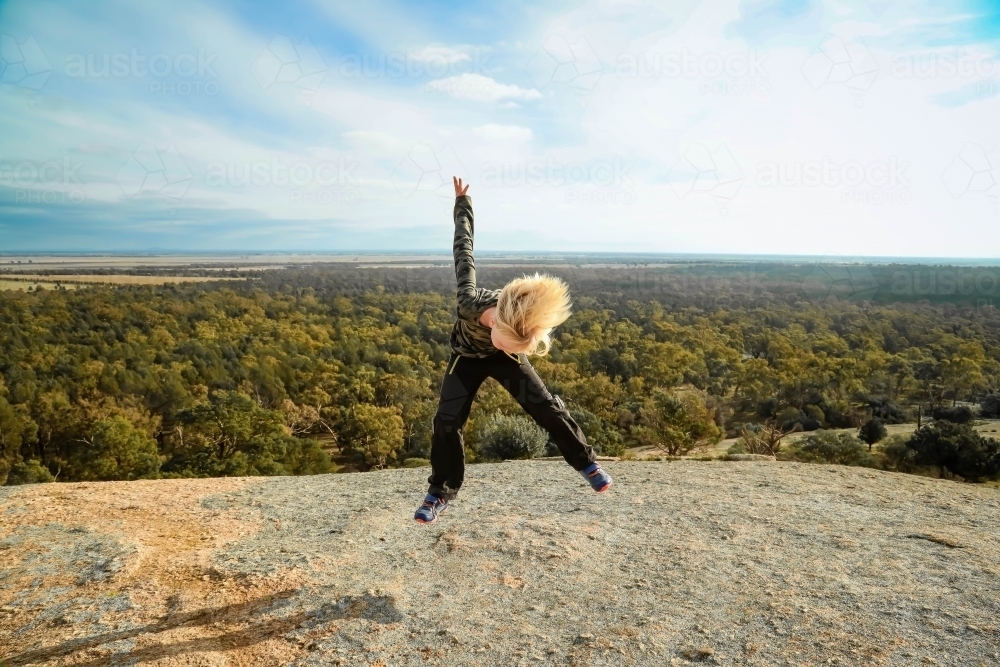 Image of Boy jumping on rock with am up in the air during nature walk ...
