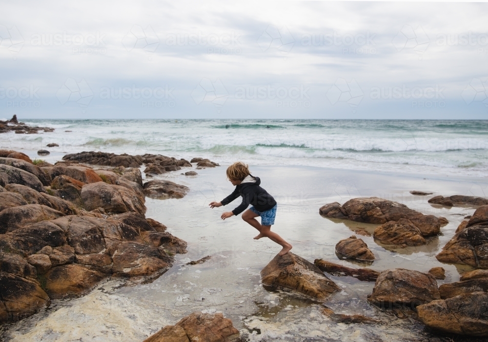 Boy jumping on rocks - Australian Stock Image