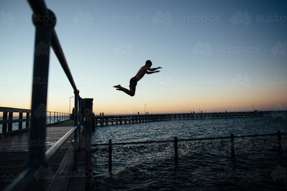 Boy leaping from pier - Australian Stock Image