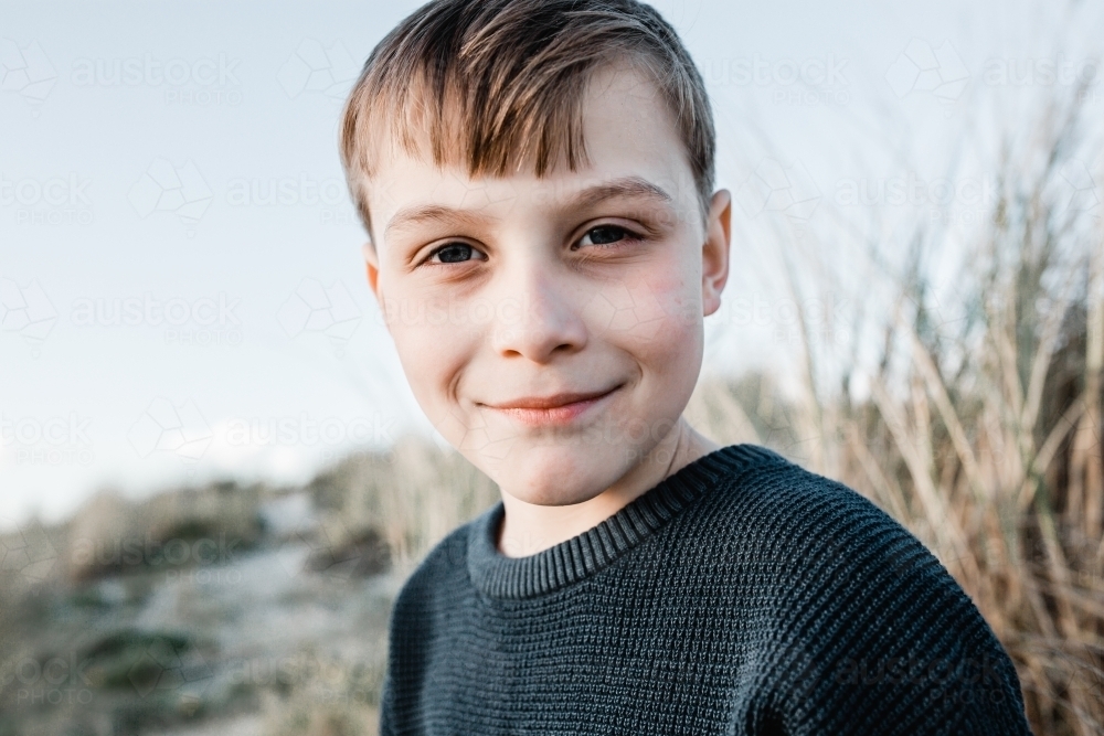 Boy looking at the camera with sand dunes in the background - Australian Stock Image