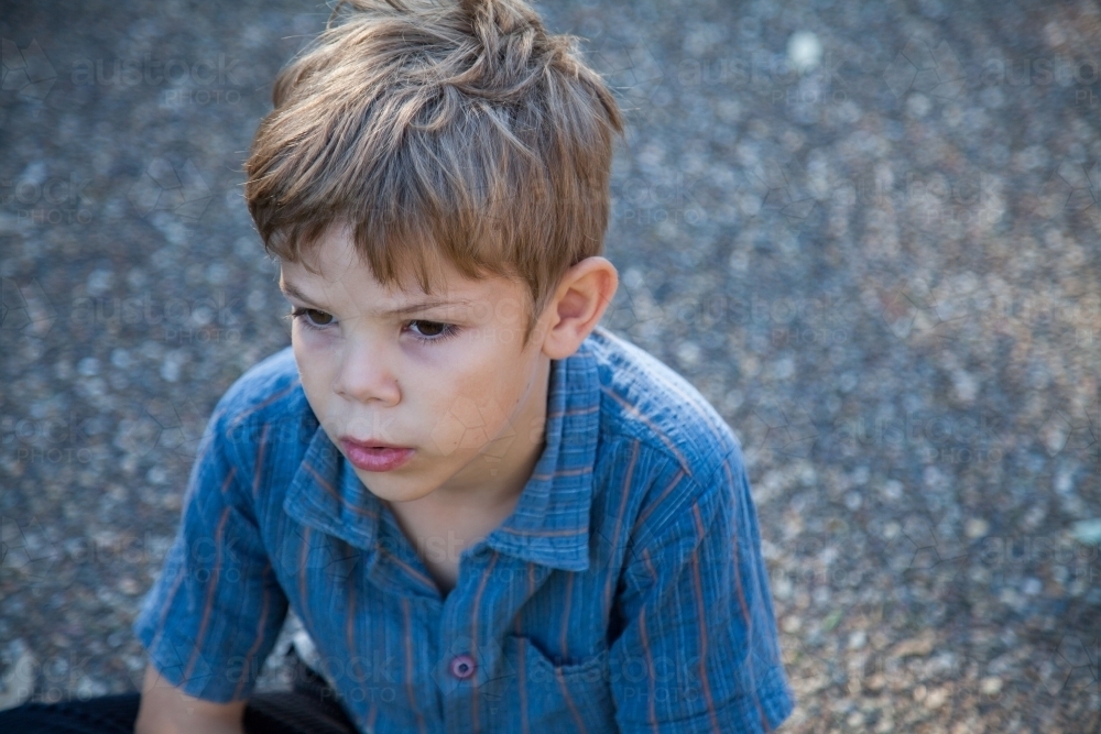 Boy looking away with sad lonely face - Australian Stock Image