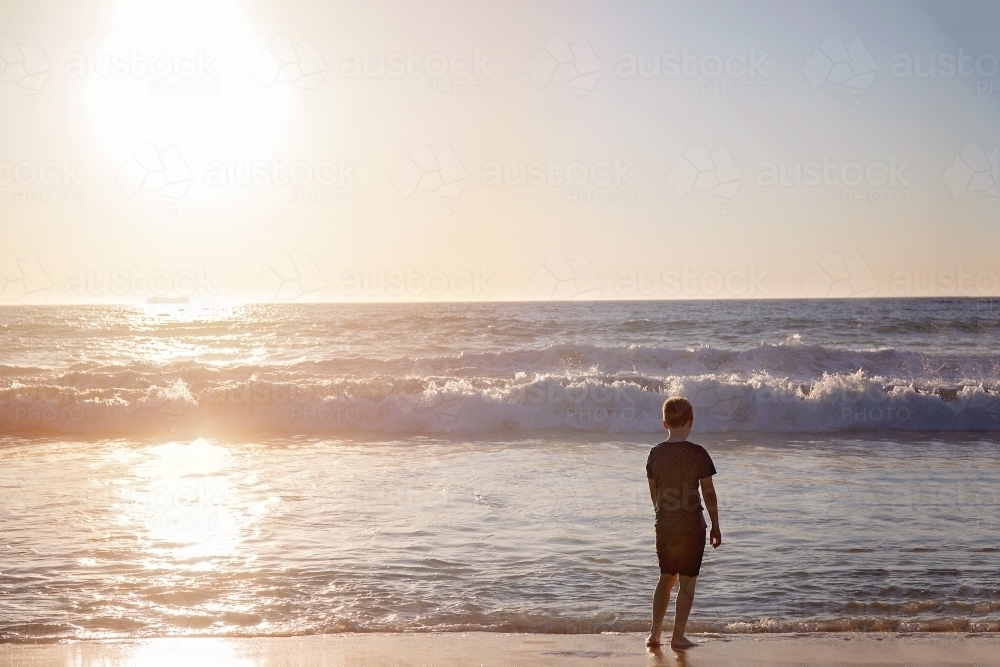 Boy Looking Out To The Ocean At Sunset - Australian Stock Image