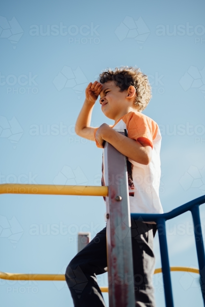 Boy on a playground looking into the distance - Australian Stock Image