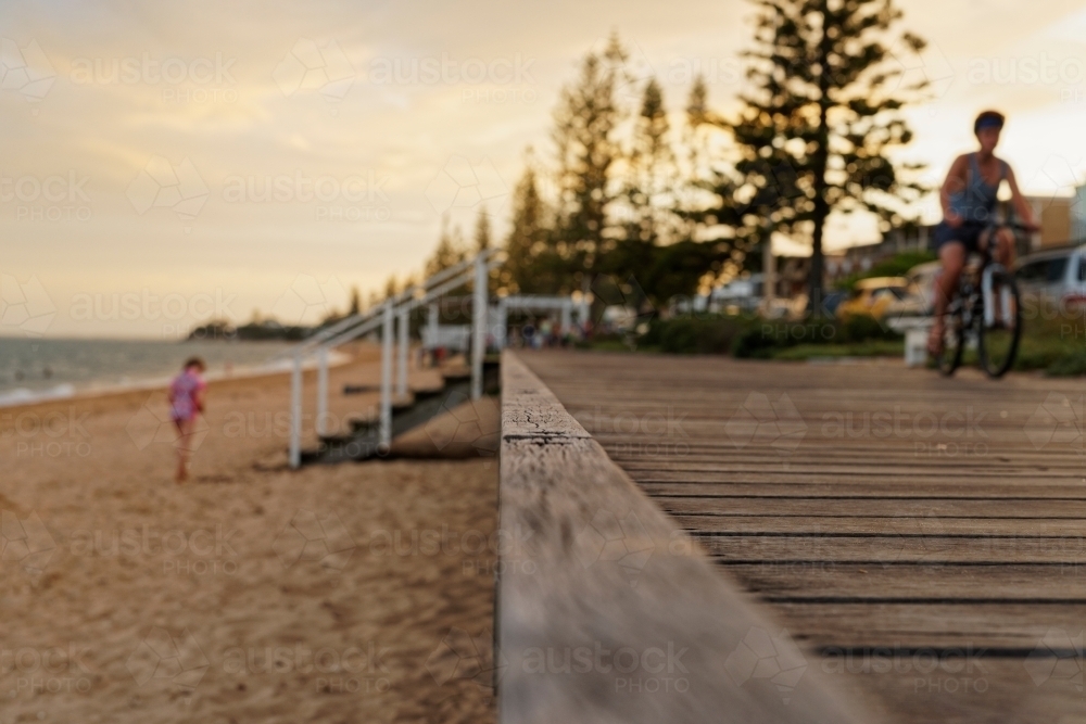 Boy on pushbike riding along coastal boardwalk - Australian Stock Image