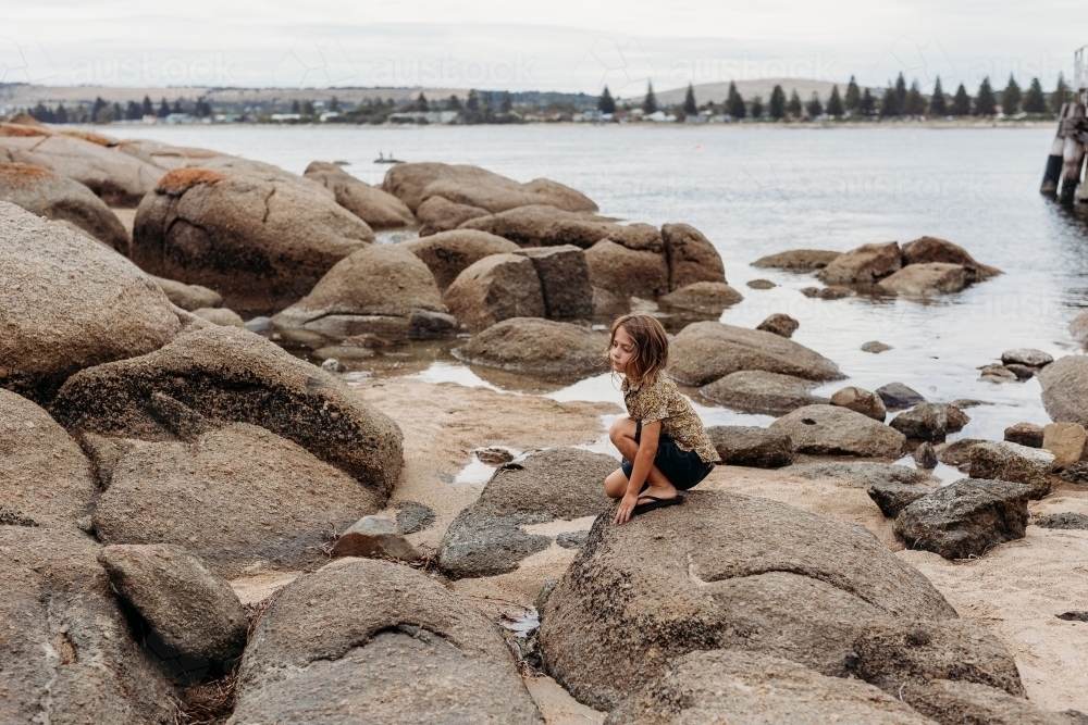 Boy on rocks near ocean - Australian Stock Image