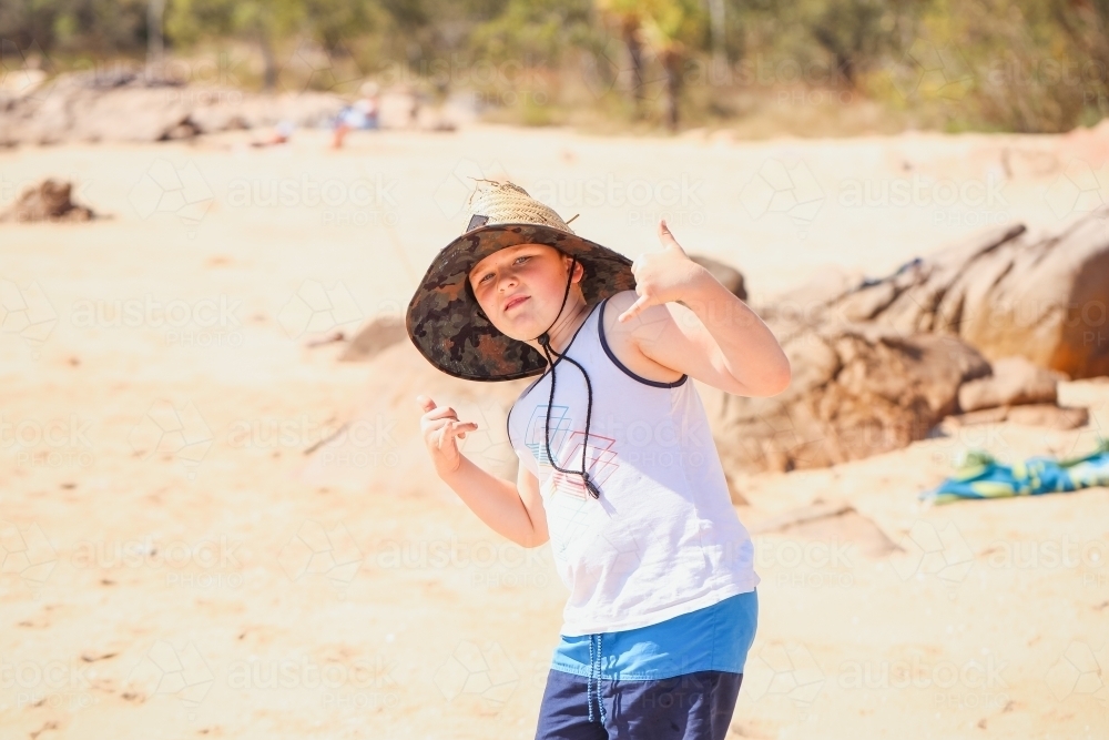 Boy on the beach wearing large straw hat at Cape Gloucester in the Whitsundays - Australian Stock Image