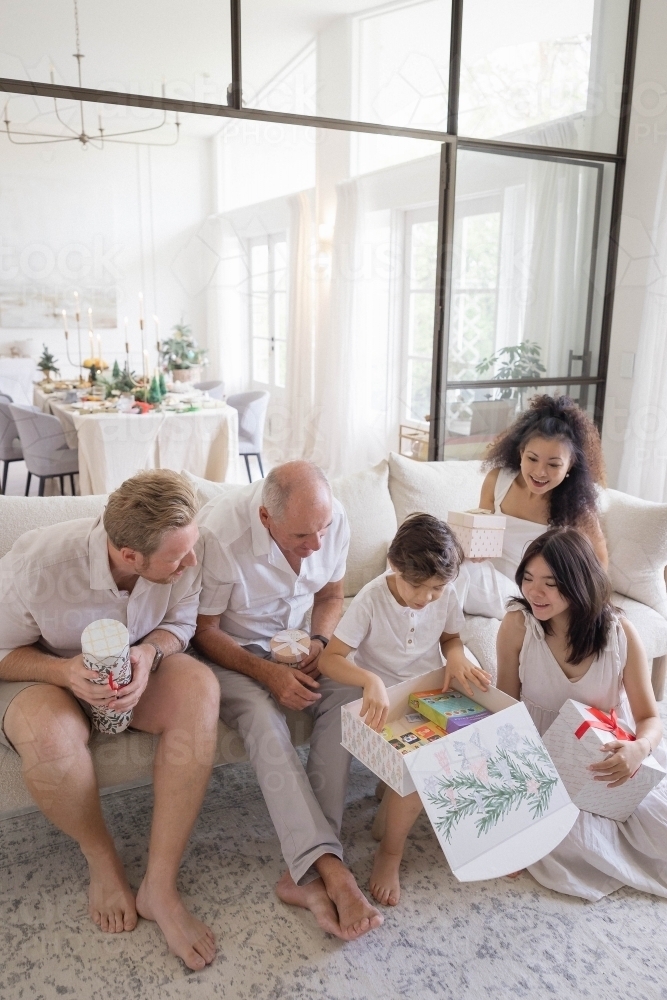 Boy opening Christmas present with family - Australian Stock Image