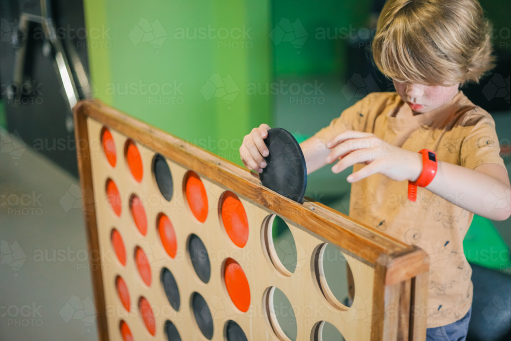 Boy playing giant connect four game - Australian Stock Image