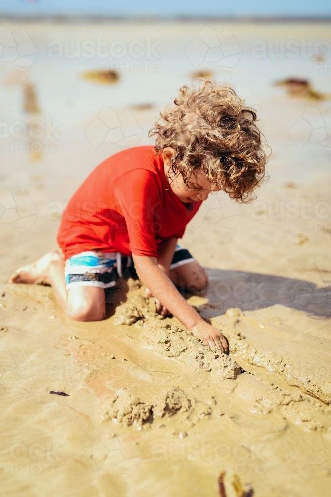 Boy playing in the sand at the beach - Australian Stock Image