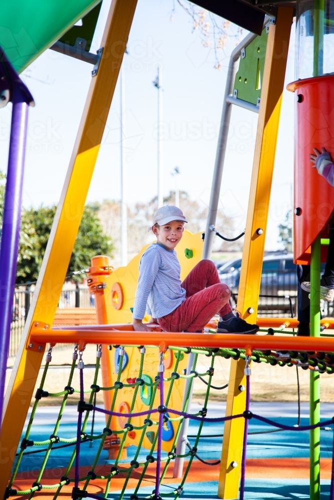 Boy playing on brightly coloured play equipment - Australian Stock Image