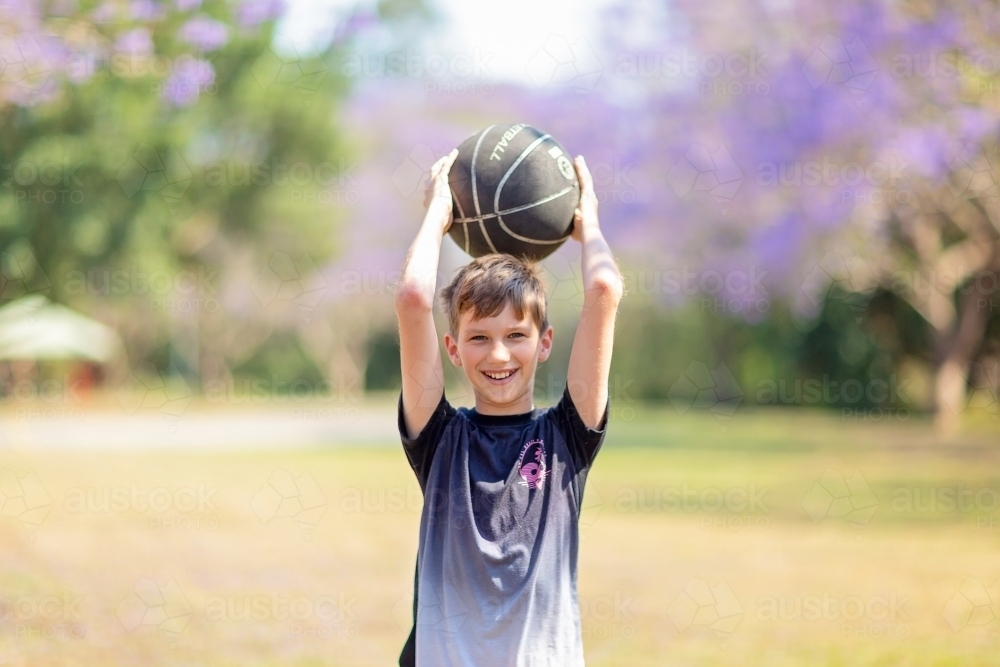 Boy playing outside with Jacaranda flowers - Australian Stock Image