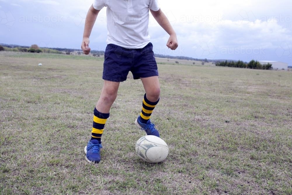 Boy playing with a football on the ground - Australian Stock Image