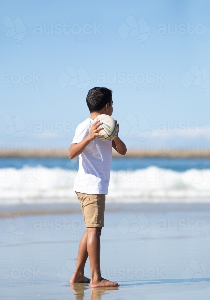 Boy playing with ball on beach - Australian Stock Image