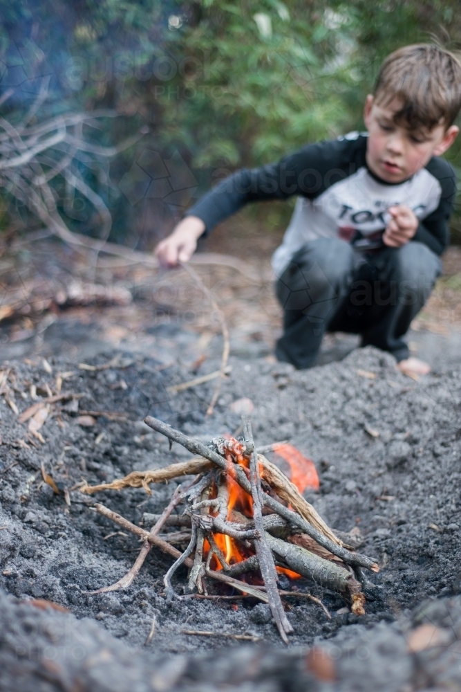Boy playing with camp fire - Australian Stock Image