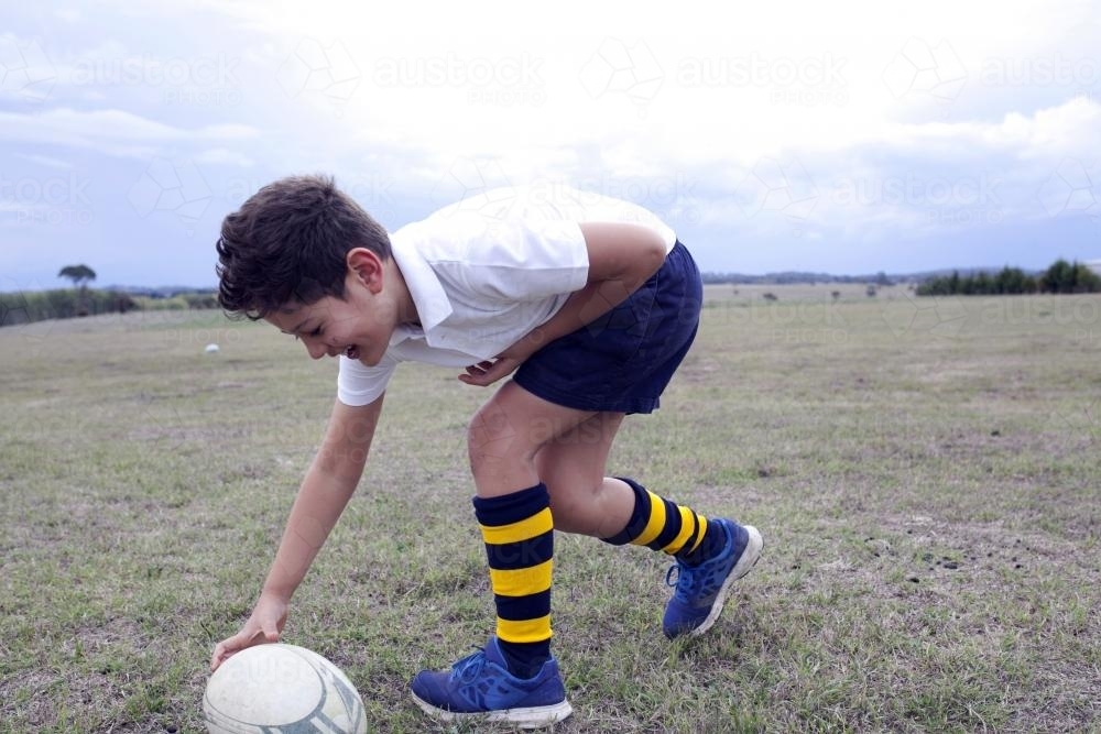 Boy playing with football on a field - Australian Stock Image