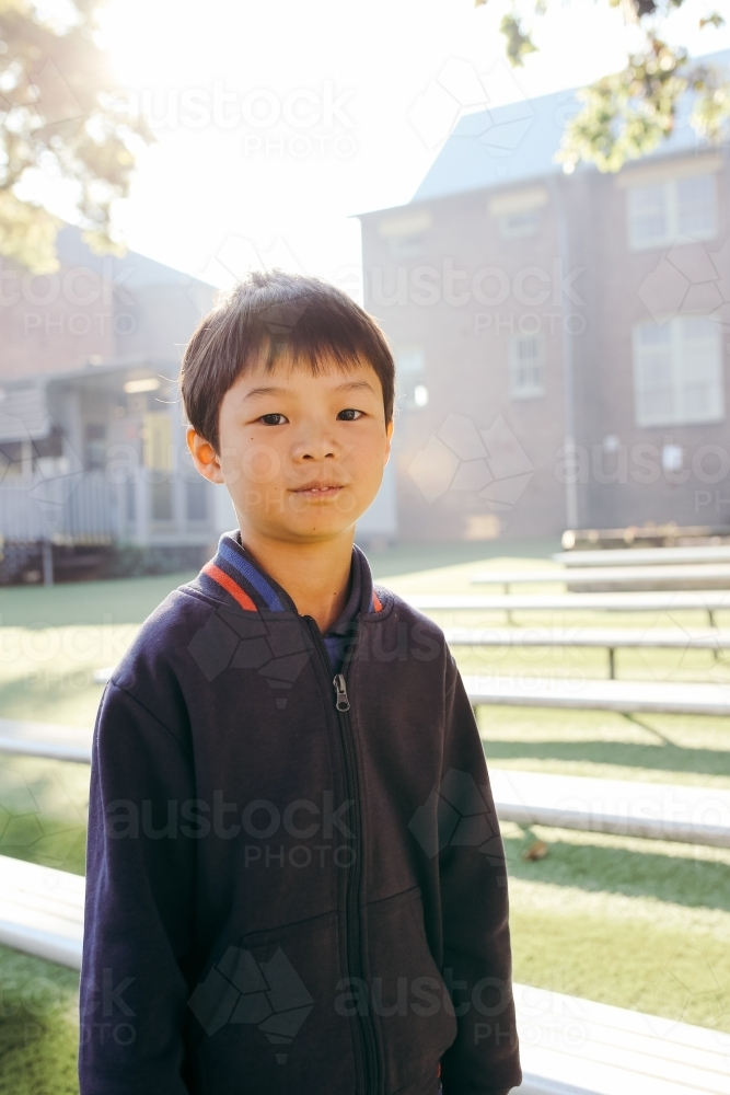 boy primary school student standing outdoors near the bench - Australian Stock Image