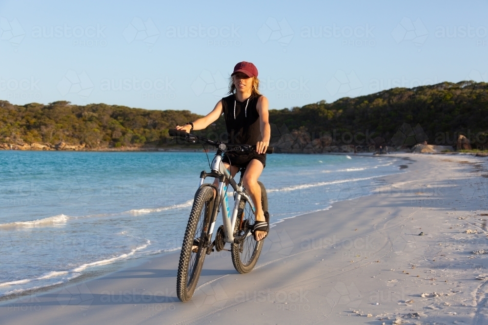 Boy riding a bike along seashore - Australian Stock Image