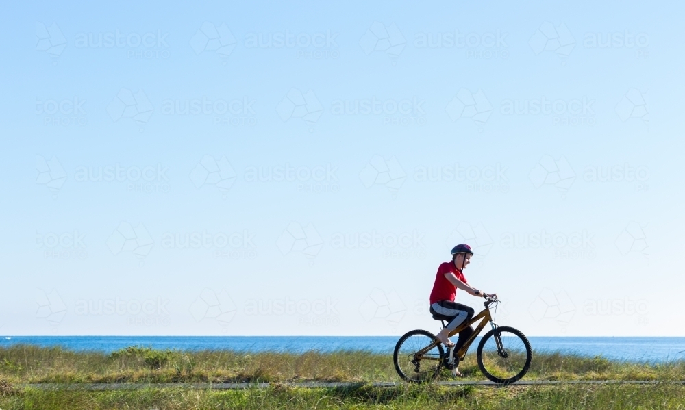 Boy riding a bike on a coastal path - Australian Stock Image